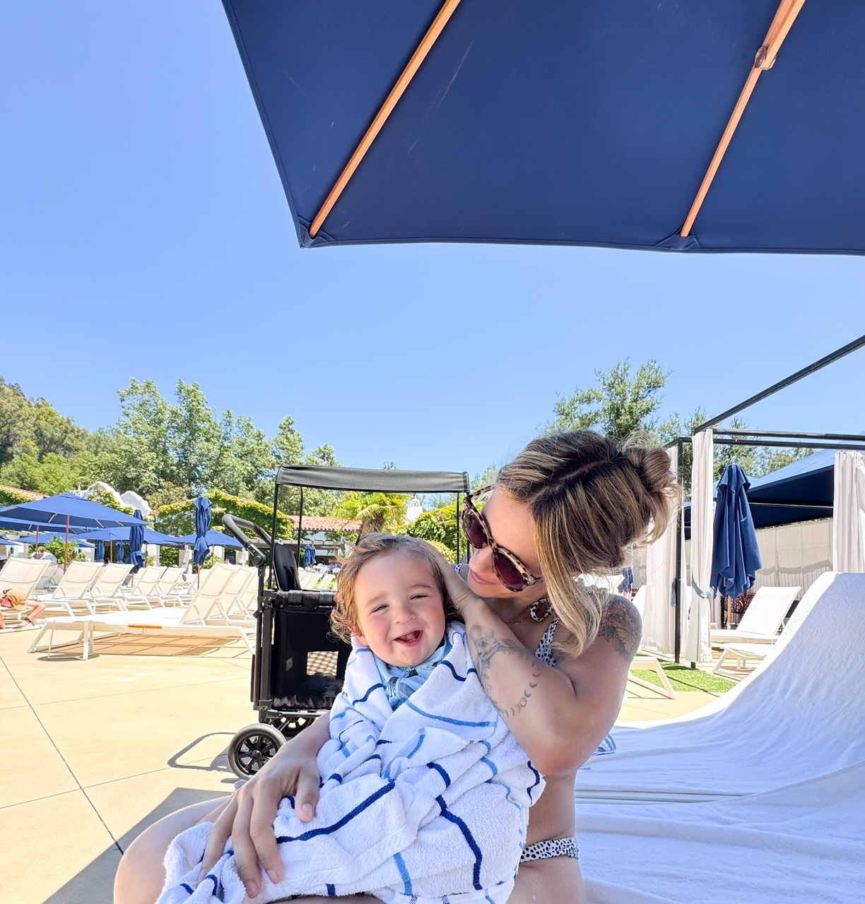 A parent holding a toddler at the edge of a shallow pool