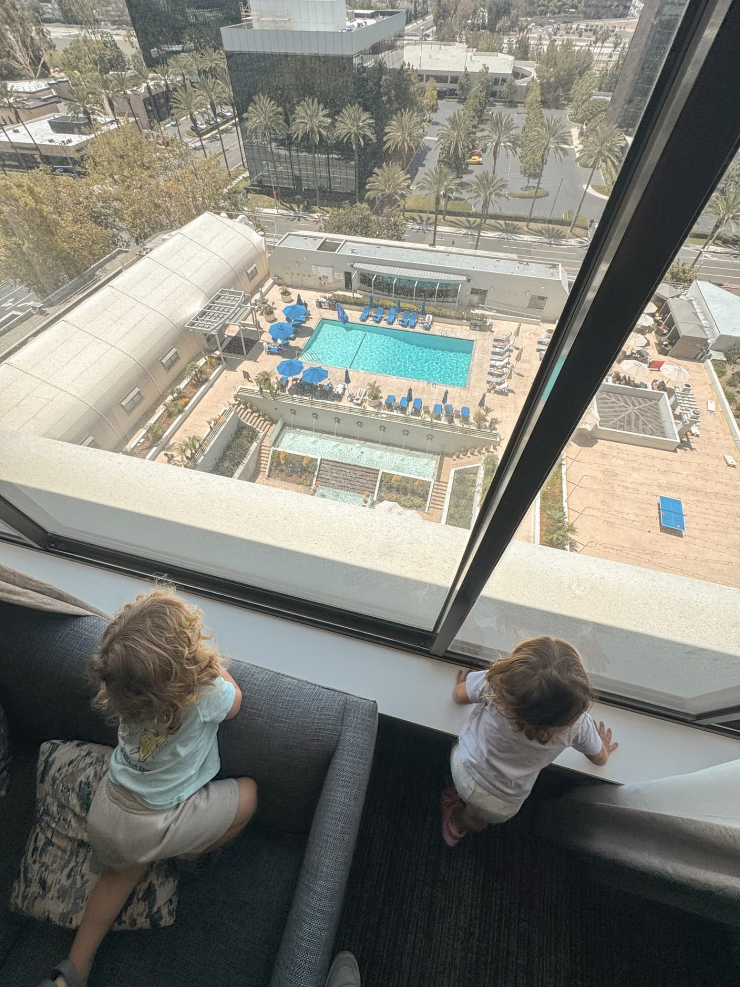 Two-year-old twins looking from their room down at the pool at The Westin South Coast Plaza